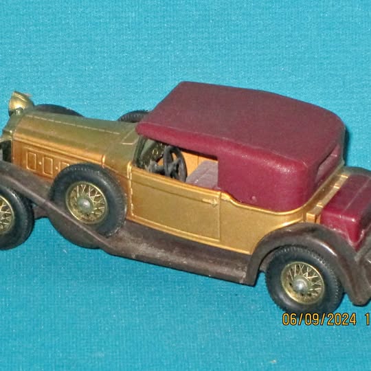 Diecast model car with gold body and maroon-red roof, side view