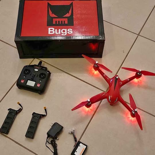 Red quadcopter drone with four propellers and handheld controller