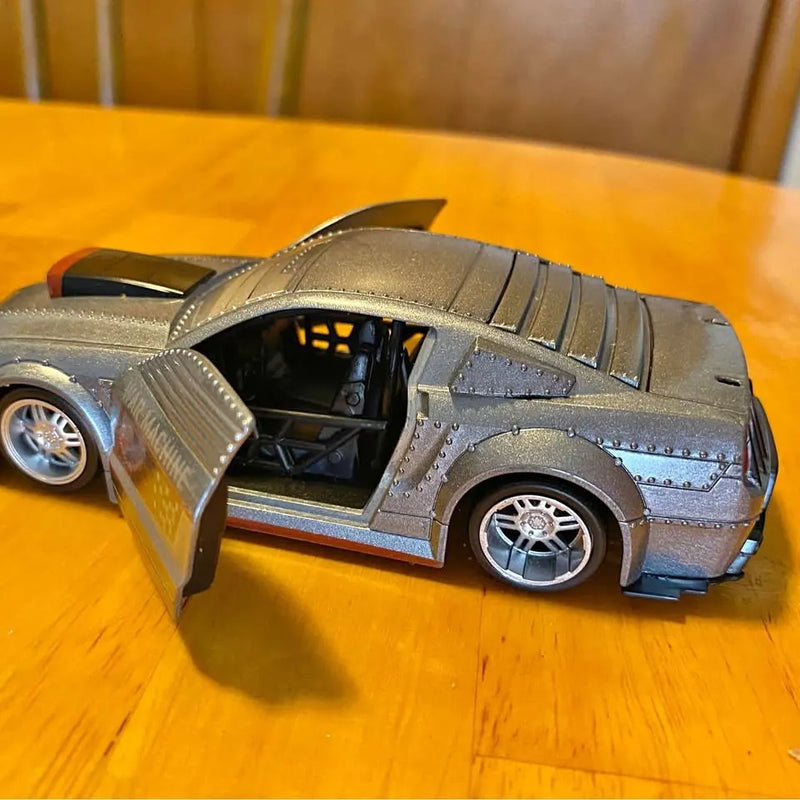 Diecast model car in dark gray with open door and detailed chrome wheels