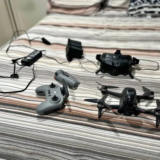 FPV drone kit with gray controller, black drone, and headset on a flat surface