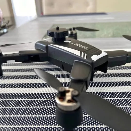 Compact quadcopter drone with camera, dark gray body and front prop guards