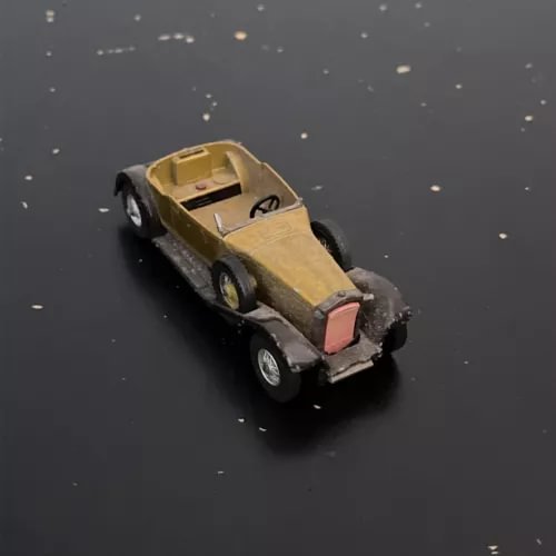 Diecast model car, olive body with pink front bumper detail, front three-quarter view