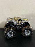 Monster truck diecast with gray body, black frame, and yellow accents, front view