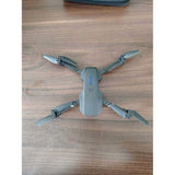 Gray foldable quadcopter drone, four propellers visible, blue light on top