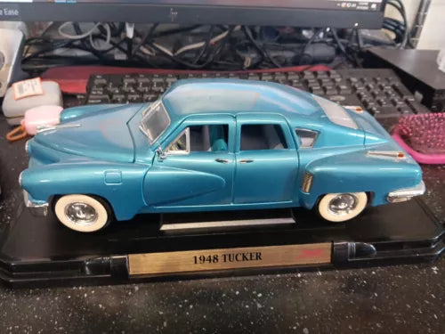 Light blue vintage diecast car model on black display stand with nameplate