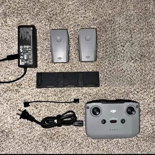 Gray drone remote controller with batteries, charger, and cables in a kit