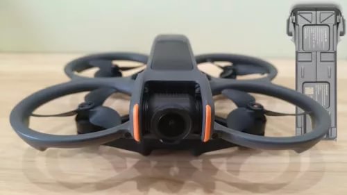 Black drone with orange front camera module and four propellers, plus battery case