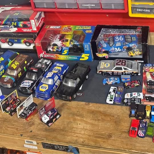 Diecast car lot with multiple NASCAR-style cars in blister packages and loose cars