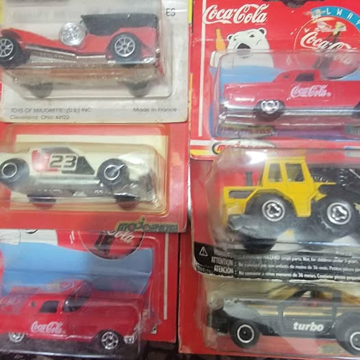 Diecast car blister packs with red, yellow, and black Coca-Cola vehicles