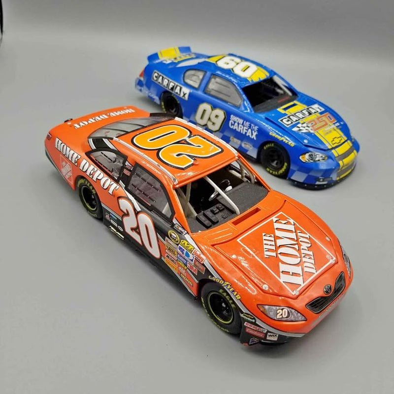 Two NASCAR diecast race cars: orange #20 and blue #09 with sponsor decals
