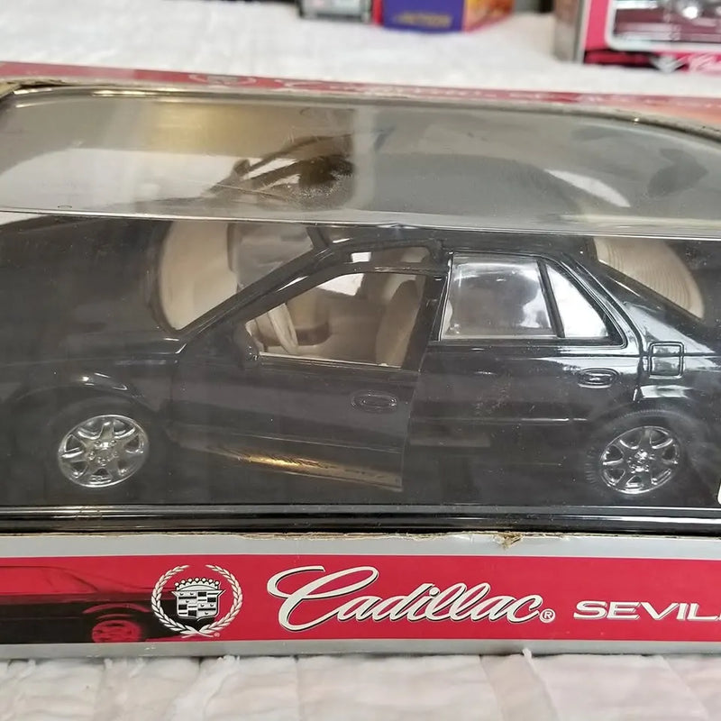 1/18 scale Cadillac diecast car, dark blue side view with chrome wheels and emblem