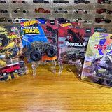 Diecast toy car in blister package with Godzilla artwork and oversized wheels