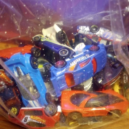Assorted diecast toy cars in clear plastic bag, blue and orange vehicles