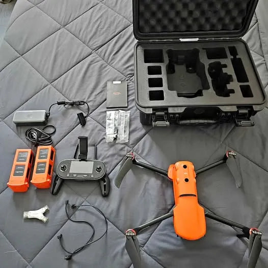 Orange drone with remote controller and batteries in black hard-shell case