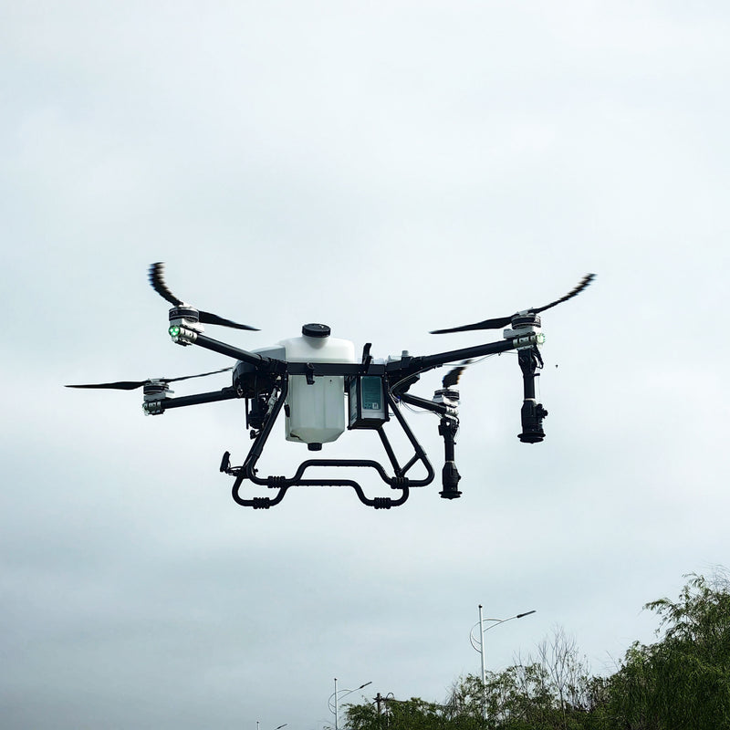 Agricultural spraying drone with central tank, four rotors, and spray nozzles