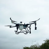 Agricultural spraying drone with central tank, four rotors, and spray nozzles