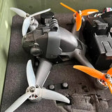 FPV drone with black body, orange propellers, and front camera module