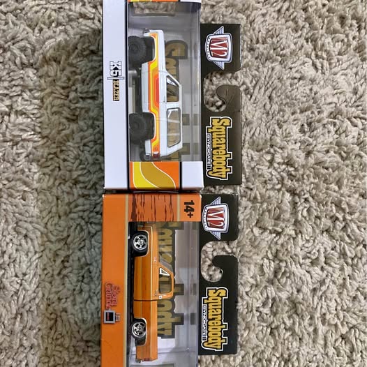 Diecast pickup truck replicas in retail boxes, orange and black stripes