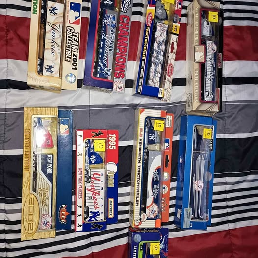 Diecast truck boxed vehicles with colorful team graphics, stacked on a striped display