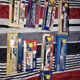 Diecast truck boxed vehicles with colorful team graphics, stacked on a striped display