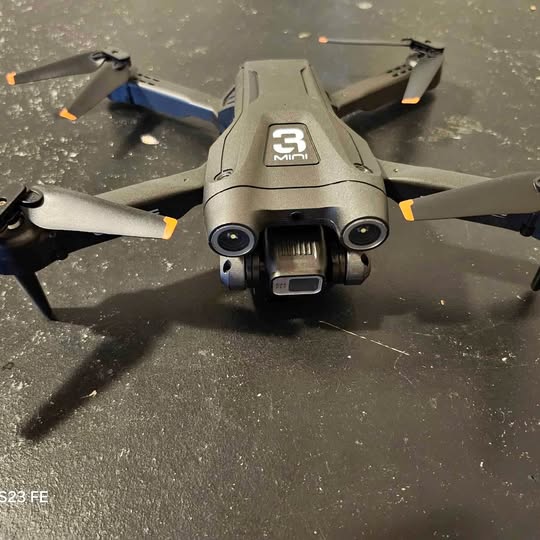 Grey quadcopter drone with front camera and propellers visible
