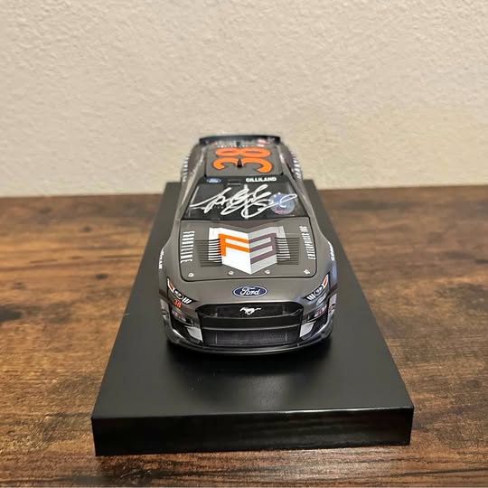 Autographed 1:24 diecast race car, black front view with racing decals and signature