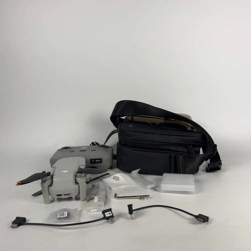 DJI Mini 2 drone with black carrying bag and accessory parts, propellers and cables
