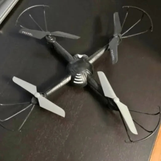 Quadcopter drone with four propellers and dark body, white blades