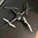 Quadcopter drone with four propellers and dark body, white blades