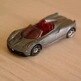 Silver-gray diecast roadster toy car with red interior, open-top cockpit view.