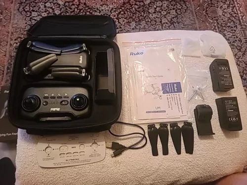 4K drone kit with remote controller in open case, batteries, prop guards, manuals