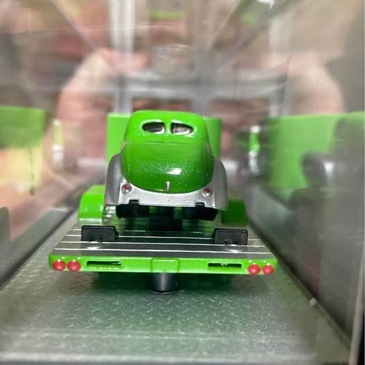Green diecast collectible vehicle with front grille and lights on display base