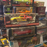 Die-cast race car toy in retail box, orange and yellow with checkered graphics