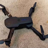 Black foldable quadcopter drone with camera, four prop arms