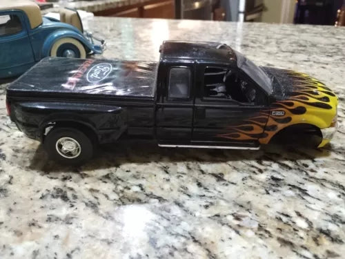 Damaged 1/25 pickup truck diecast model, black with yellow flame graphics