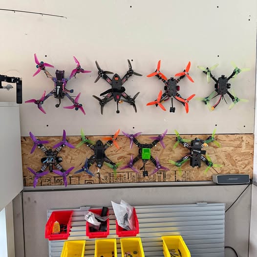 Racing multirotor quadcopter drones with colored propellers on display board