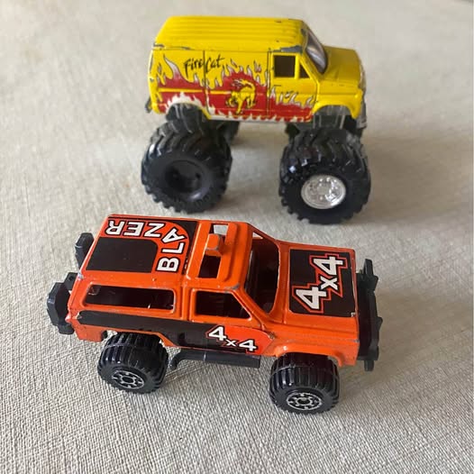 Orange 4x4 diecast monster truck and yellow Firecat pickup, toy cars with oversized tires