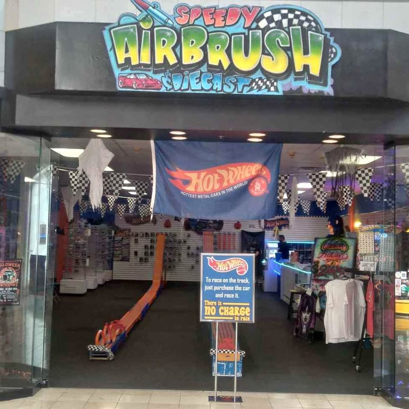 Airbrush shop storefront sign with t-shirt display racks and custom tees
