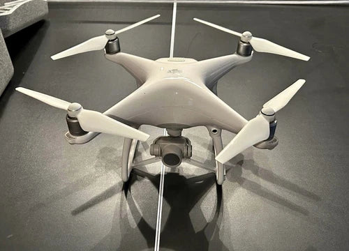 White DJI Phantom 4 quadcopter drone with four propellers and front camera