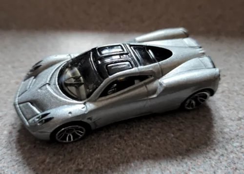 Silver diecast toy supercar with black cockpit detail, side view, open door