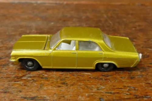 Gold diecast sedan car, side view with detailed wheels and windows