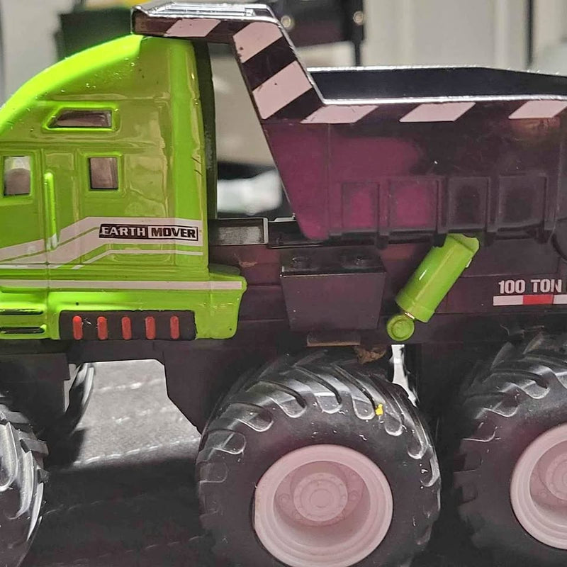 Green and maroon diecast dump truck toy with large rugged wheels and tipping bed