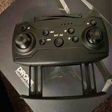 Black drone remote controller with dual thumbsticks and built-in screen