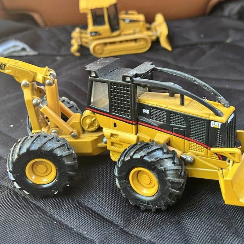 Yellow and black diecast skidder model, front-left view with detailed wheels and cab