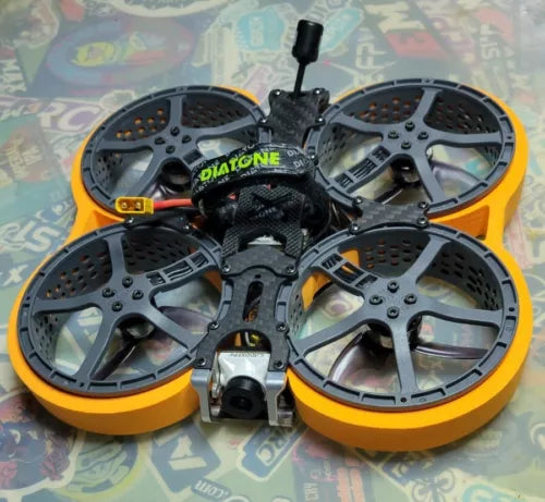 Cinewhoop FPV drone with four gray prop guards and orange frame rings, central camera