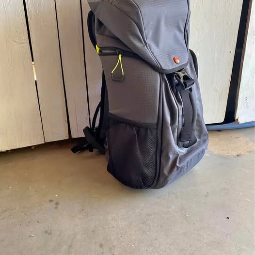 Grey and black backpack-style drone pack with front mesh pocket and side straps