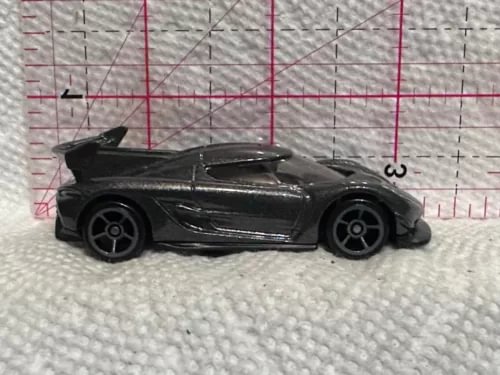 Black toy diecast sports car with side profile and raised wheels detail