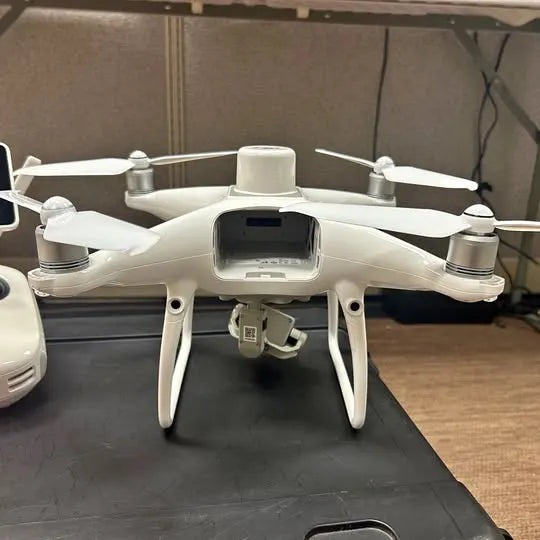 White quadcopter drone with front camera module and four propellers