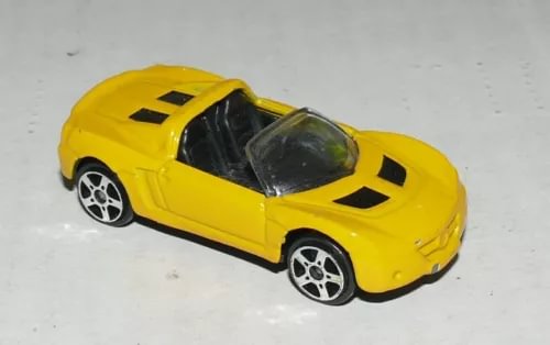 Yellow 1:64 diecast sports car with black hood stripes and silver wheels