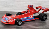 Red Formula 1 diecast race car with black tires and Martini-style decals